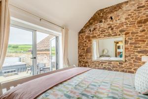 a bedroom with a stone wall and a bed with a mirror at The Farm Office in Tiverton