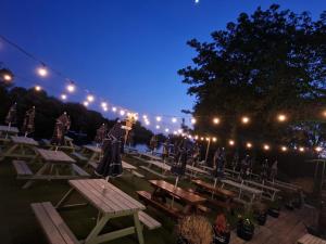 un grupo de mesas de picnic y luces por la noche en The Riverside, en Lechlade