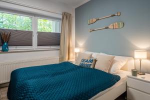 a bedroom with a bed with a blue comforter and a window at VIVID - Traumwohnung ruhig und strandnah gelegen in Varel