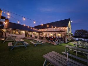 un edificio con mesas de picnic en el patio por la noche en The Riverside, en Lechlade