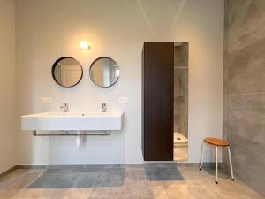 een badkamer met een wastafel en 2 spiegels bij Achter de Hegge in Riemst