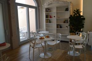 una stanza con tavoli e sedie bianchi e una finestra di TANIT ROOMS & SPA a Villasimius