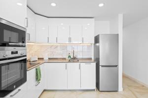 a kitchen with white cabinets and a stainless steel refrigerator at Neptuno Ocean View, Beach line with Pool in Puerto de Santiago
