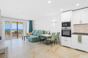 a living room with a couch and a table with chairs at Neptuno Ocean View, Beach line with Pool in Puerto de Santiago +28 photos