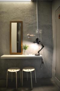 a vanity with two stools and a mirror and a lamp at GRAYHAUS INN Ipoh in Ipoh