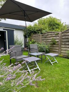 twee picknicktafels en een paraplu in een tuin bij mooihusen in Norden
