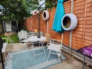 un patio con mesa, sillas y sombrilla en Spacious Room with Garden in Croydon London en South Norwood