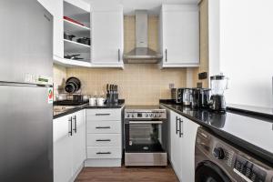 a kitchen with white cabinets and stainless steel appliances at Luxury studio in Discovery Gardens near metro in Dubai