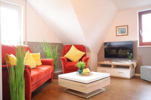 a living room with two red chairs and a tv at Ferienwohnung Helgoland in Dorum-Neufeld