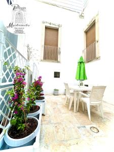 un patio con fiori, tavolo e sedie di Palazzo Mastrovito a Martina Franca