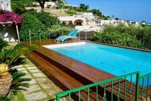 una piscina con terrazza in legno accanto a una casa di Villa capri con giardino e piscina a Capri