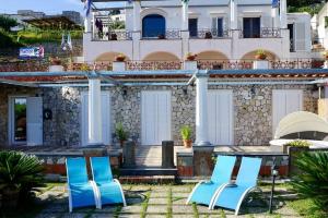 two blue chairs and a table in front of a house at Villa capri con giardino e piscina in Capri