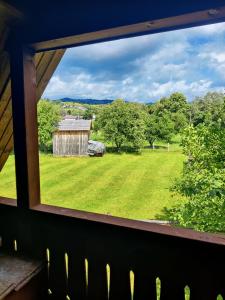 a window view of a field and a barn at Pensiunea Casa Alexandra in Lunca Ilvei