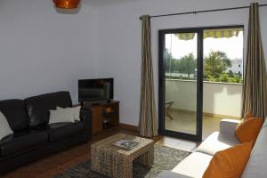 ein Wohnzimmer mit einem Sofa und einem TV in der Unterkunft Condominio Vilita, T1-Lt-5,F Pera-Silves in Pêra