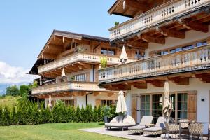 a building with chairs and umbrellas in front of it at Tennerhof Luxury Chalets in Kitzbühel +51 photos