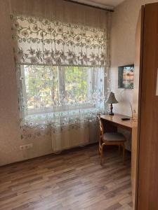 Zimmer mit einem Schreibtisch und einem Fenster mit einem Fenstervorhang in der Unterkunft Paradize in Daugavpils