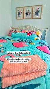 a bed with colorful sheets and pillows on it at Hmsty D Hutan Kampung Alor Setar (Muslim) 