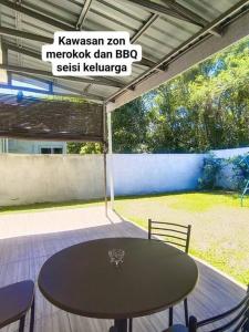 a table and chairs on a patio with a sign at Hmsty D Hutan Kampung Alor Setar (Muslim) 