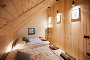 two beds in a room with wooden walls at Alpine Cottage Golica in Jesenice