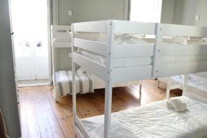 um quarto com beliches brancos num quarto em A Beira Hostel em Aveiro