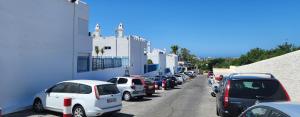 eine Reihe von Autos, die auf einer Straße neben einem Gebäude geparkt sind in der Unterkunft Bungalow del sol in Playa del Ingles