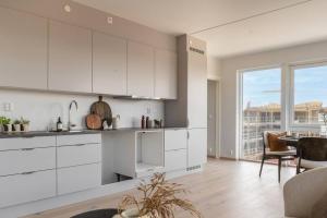 uma cozinha com armários brancos e uma grande janela em New Build Luxury Apartment OSLO em Lorenskog