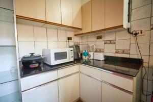 a small kitchen with a microwave and a stove at The Forest House - Kawuku-Bunga in Kampala