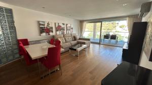 ジブラルタルにあるOcean Village Luxury 2 Bed 2 Bath Apartment - amazing views - pools and jacuzzisのリビングルーム(ソファ、テーブル、赤い椅子付)