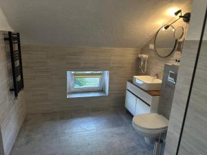 łazienka z toaletą, umywalką i oknem w obiekcie Pensjonat Pod Wozem w mieście Trzebiatów