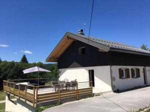 Una pequeña casa con terraza y sombrilla. en La Fromagerie - Gîte d'exception à La Mouille, en La Mouille