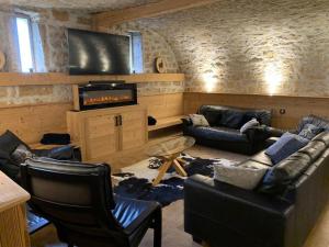 a living room with couches and a flat screen tv at GITE La fromagerie Haut Jura 