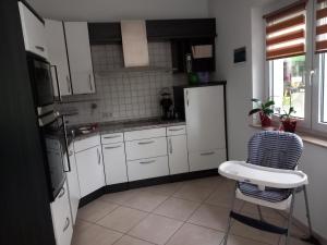 a kitchen with white cabinets and a chair and a refrigerator at Wohlfühloase in Suhl +5 photos