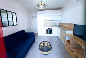 un soggiorno con un divano blu e una cucina di Le MARTY 9 Vue Mer Loggia Climatisé Piscine Centre a Sète