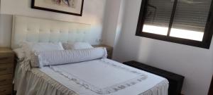 a bedroom with a bed with white sheets and a window at APART-DUPLEX-ATICO Tomares in Tomares