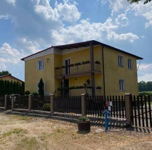 a yellow house with a fence in front of it at Apartament Kosynka 