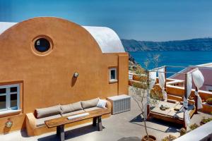 a house with a couch and a table on a balcony at Όμορφη βίλα στην Οία με θέα στην καλντέρα in Oia