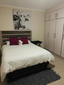 a bedroom with a large white bed with red pillows at E & P Cave in Swakopmund