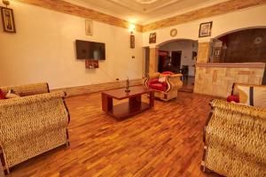 uma sala de estar com cadeiras, uma mesa e uma televisão em The Forest House - Kawuku-Bunga em Kampala