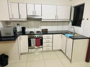 a kitchen with white cabinets and a stove and a microwave at E & P Cave in Swakopmund