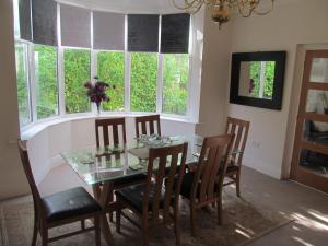 a dining room with a glass table and chairs and windows at junction house in Stockton-on-Tees