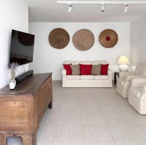 een woonkamer met een witte bank en rode kussens bij casARCHÉ in Porto Torres
