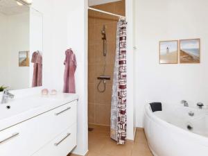 ein weißes Badezimmer mit einer Badewanne und einem Waschbecken in der Unterkunft Captivating Holiday home in L kken with Whirlpool in Løkken