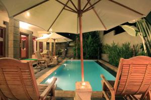 a swimming pool with two chairs and an umbrella at Superb family friendly villa with pool and only 500 metres from beach in Montongbuwoh +6 photos