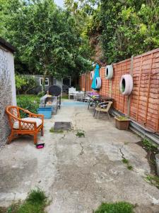 a patio with a wooden fence and chairs and a bench at Spacious Room with Garden in Croydon London in South Norwood