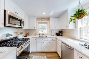 a kitchen with white cabinets and a stove at The Cape House in Cotuit