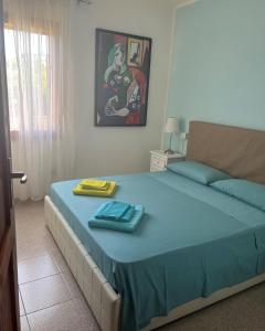 Villetta Indipendente Sardegna في فيلابوتزو: غرفة نوم بسرير وبطانية زرقاء وصورة