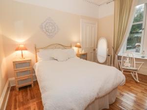 a bedroom with a white bed and a chair at Silverbells in Millport