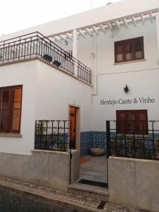 a white house with a gate and a balcony at Alentejo Cante & Vinho in Ferreira do Alentejo