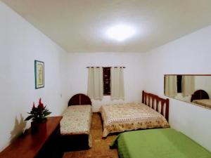 a bedroom with two beds and a desk and a window at Sitio em Santa Isabel Recanto da Tranquilidade in Santa Isabel