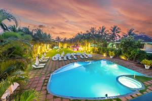 una vista aérea de una piscina con sillas y palmeras en O Hotel Goa, Candolim Beach en Candolim